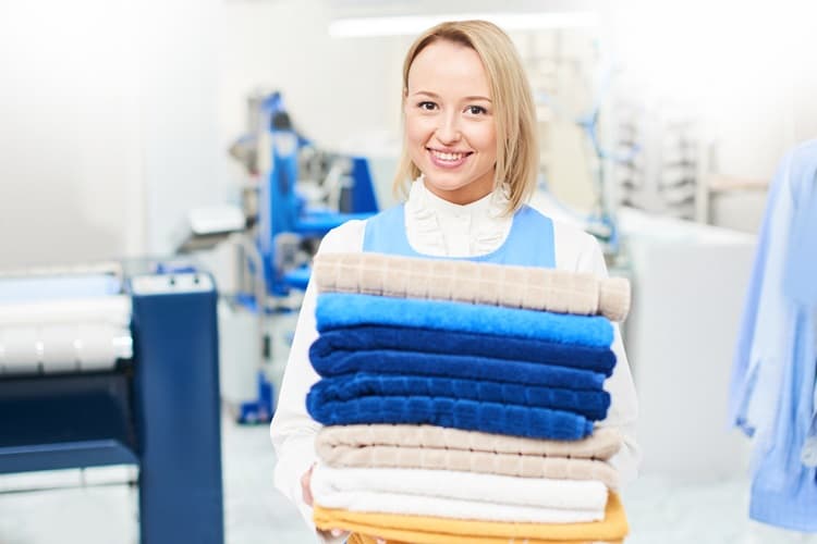 Clothes folding A smiling lady holding folding clothes in a laundry shop